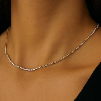 Silver chain necklace on a person's neck against a neutral background