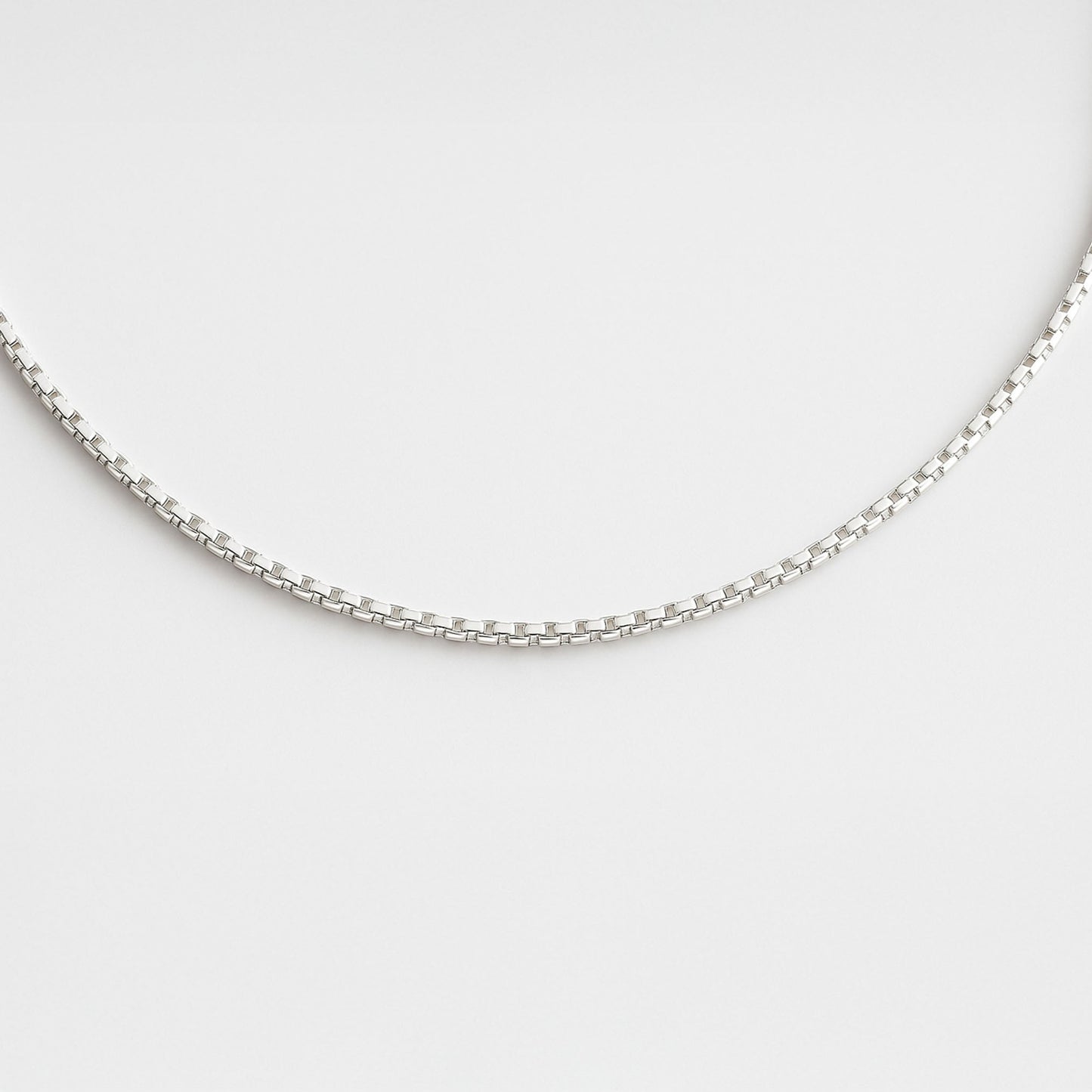 Silver chain necklace on a light gray background