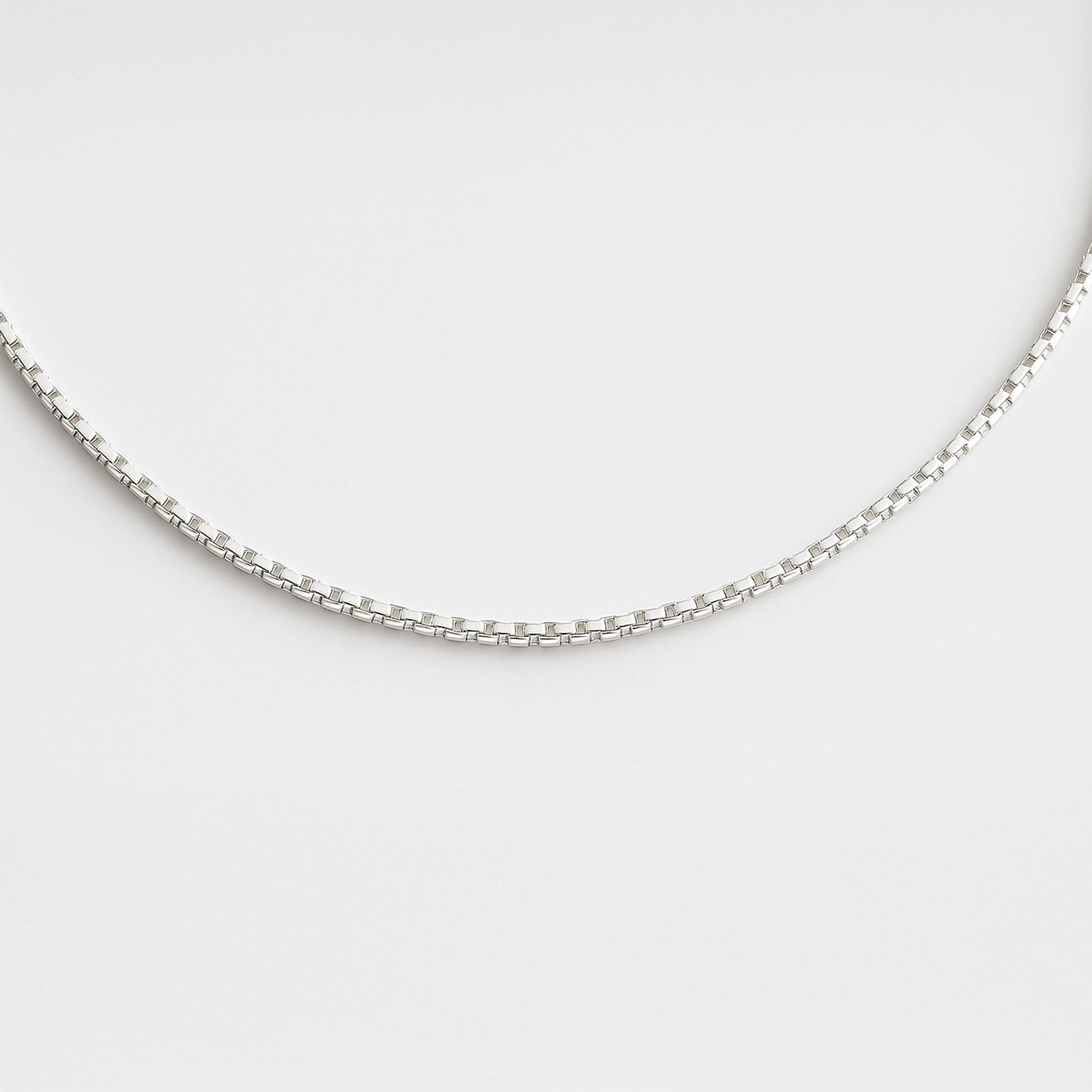 Silver chain necklace on a light gray background