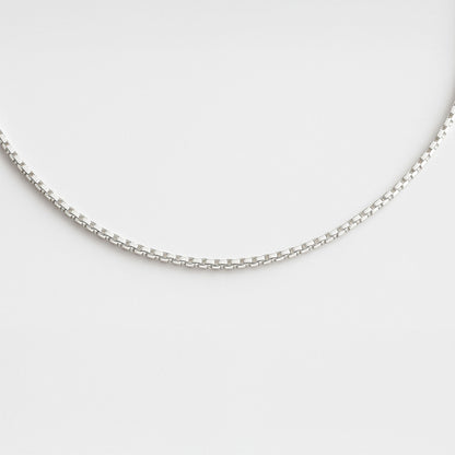 Silver chain necklace on a light gray background